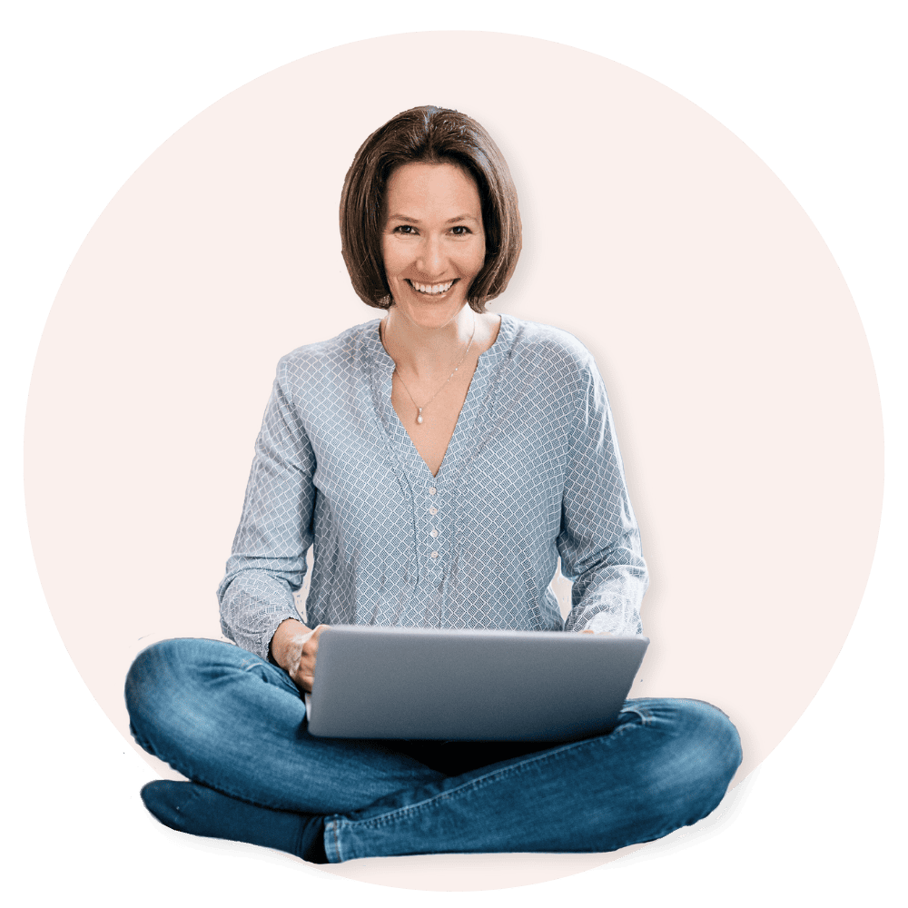 Das Bild zeigt eine lächelnde Frau, die mit einem Laptop auf dem Schoß sitzend dargestellt ist.