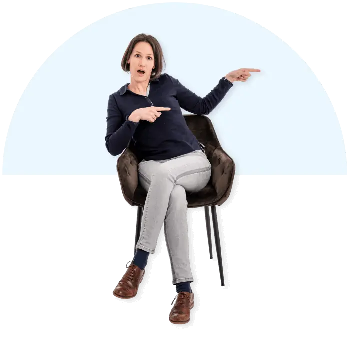 Eine Person sitzt auf einem Stuhl und zeigt mit beiden Händen in verschiedene Richtungen.