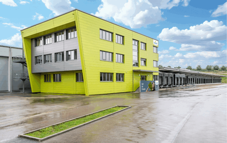 Das moderne, grüne Gebäude mit einem innovativen Design steht für frische Lebensmittelqualität und zeitgemäße Logistik. Mit einem hellen, einladenden Layout und funktionalen Anlieferungen ist es ein wichtiger Standort für effiziente Warenverteilung und nachhaltige Geschäftspraktiken.